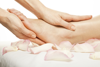 woman foot receiving gentle massage on bed with rose petals, isolated with work path